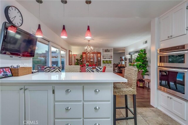1717 Cumbre Dr, San Pedro, CA 90732 - kitchen with stainless steel double oven, light countertops, a peninsula, a chandelier, and decorative light fixtures