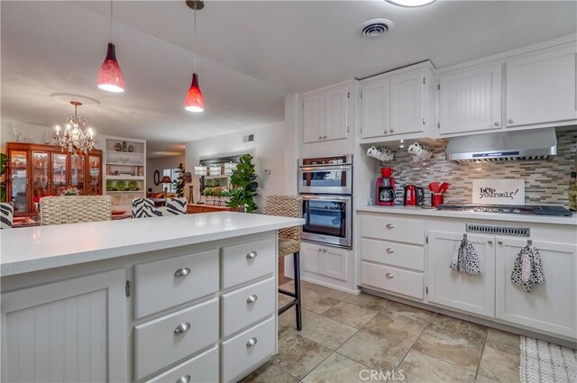 1717 Cumbre Dr, San Pedro, CA 90732 - kitchen featuring under cabinet range hood, gas cooktop, light countertops, tasteful backsplash, and double oven