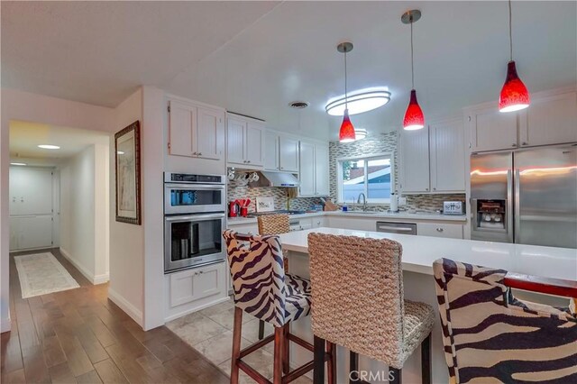 1717 Cumbre Dr, San Pedro, CA 90732 - kitchen with appliances with stainless steel finishes, light countertops, backsplash, wood finished floors, and baseboards
