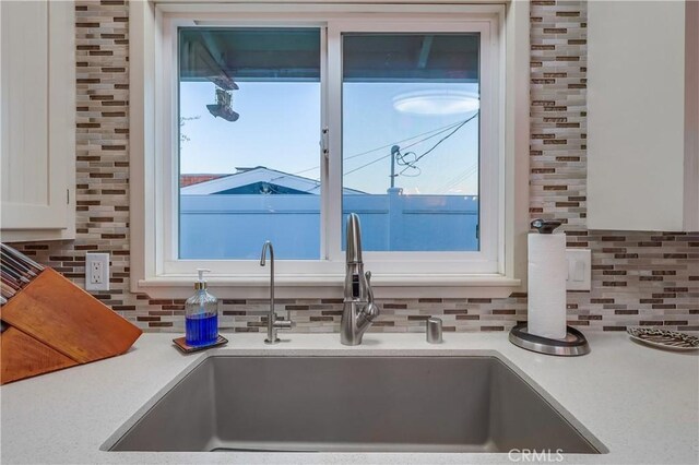 1717 Cumbre Dr, San Pedro, CA 90732 - kitchen view of a sink, tasteful backsplash, white cabinetry, and light countertops