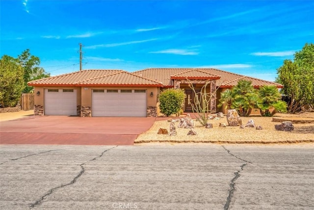 57934 Juarez Dr, Yucca Valley, CA 92284 - view of front of home with stone siding, stucco siding, a garage, a tiled roof, and concrete driveway