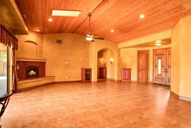 57934 Juarez Dr, Yucca Valley, CA 92284 - unfurnished living room with wooden ceiling, arched walkways, tile patterned floors, a warm lit fireplace, and ceiling fan