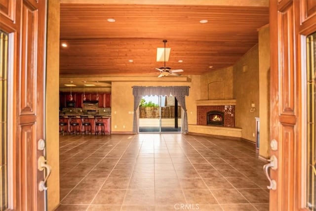 57934 Juarez Dr, Yucca Valley, CA 92284 - unfurnished living room with wood ceiling, a lit fireplace, tile patterned flooring, a ceiling fan, and recessed lighting