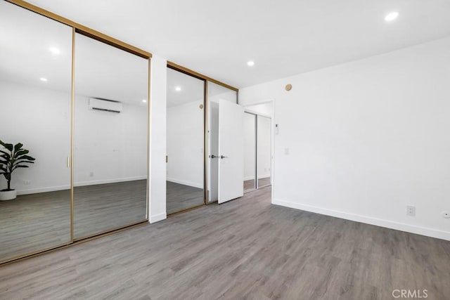 20930 Parthenia St Unit 206, Canoga Park, CA 91304 - unfurnished bedroom featuring two closets, a wall unit AC, wood finished floors, baseboards, and recessed lighting