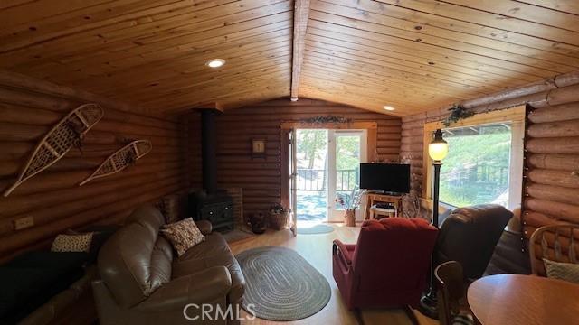 33796 Cedar Pines Ln, Green Valley Lake, CA 92341 - living area featuring a wood stove, wooden ceiling, rustic walls, and plenty of natural light