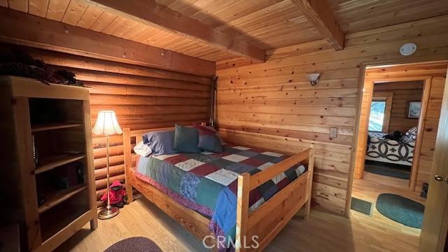 33796 Cedar Pines Ln, Green Valley Lake, CA 92341 - bedroom with wood finished floors, wood ceiling with exposed beams, and log walls