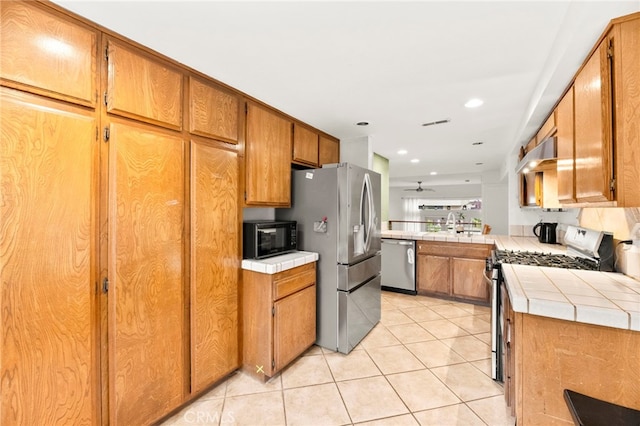 5715 Baltimore Dr Unit 35, La Mesa, CA 91942 - kitchen with appliances with stainless steel finishes, tile countertops, light tile patterned flooring, brown cabinetry, and recessed lighting