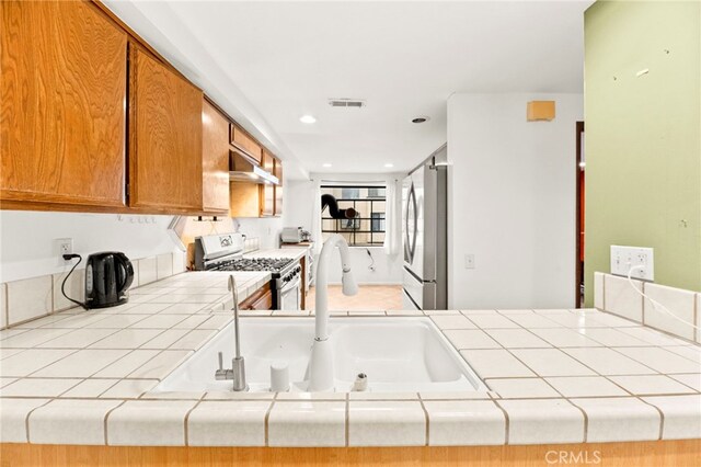 5715 Baltimore Dr Unit 35, La Mesa, CA 91942 - kitchen with range with gas stovetop, freestanding refrigerator, tile countertops, under cabinet range hood, and a sink