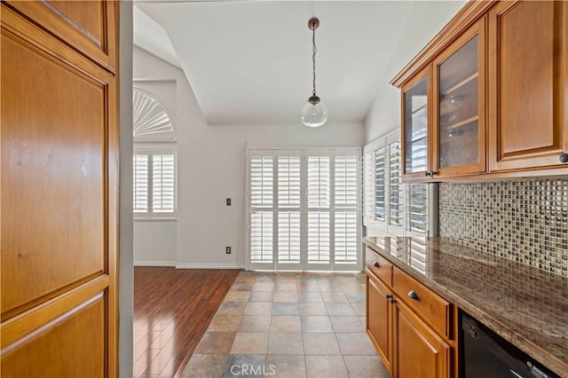 26966 Flo Ln Unit 318, Canyon Country, CA 91351 - kitchen with lofted ceiling, decorative backsplash, dark stone countertops, brown cabinetry, and glass insert cabinets
