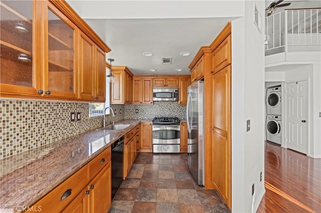 26966 Flo Ln Unit 318, Canyon Country, CA 91351 - kitchen with stainless steel appliances, estacked washer and dryer, stone counters, brown cabinetry, and tasteful backsplash