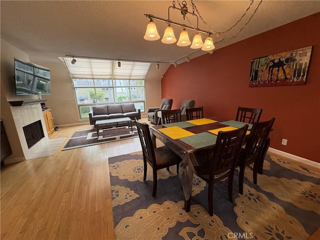 3381 Bandit Cir, Huntington Beach, CA 92649 - dining room with rail lighting, light wood finished floors, a fireplace with flush hearth, and a textured ceiling