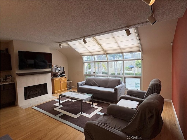 3381 Bandit Cir, Huntington Beach, CA 92649 - living room with track lighting, light wood-type flooring, a tiled fireplace, and a textured ceiling