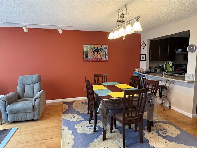 3381 Bandit Cir, Huntington Beach, CA 92649 - dining room featuring rail lighting, light wood-style floors, and a textured ceiling