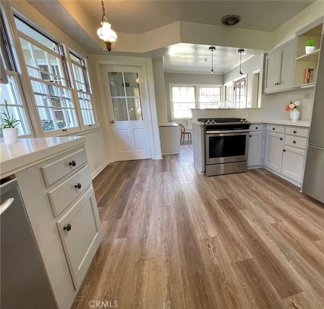 3275 N D St, San Bernardino, CA 92405 - kitchen featuring stainless steel appliances, a peninsula, wood finished floors, light countertops, and pendant lighting