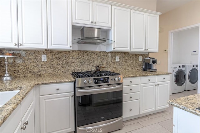 38161 Desert Hawk Dr, Palmdale, CA 93552 - kitchen with stainless steel gas stove, washer and dryer, wall chimney exhaust hood, backsplash, and white cabinets