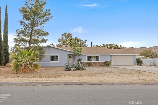 7010 Airway Ave, Yucca Valley, CA 92284 - ranch-style house with stucco siding, driveway, an attached garage, and stone siding