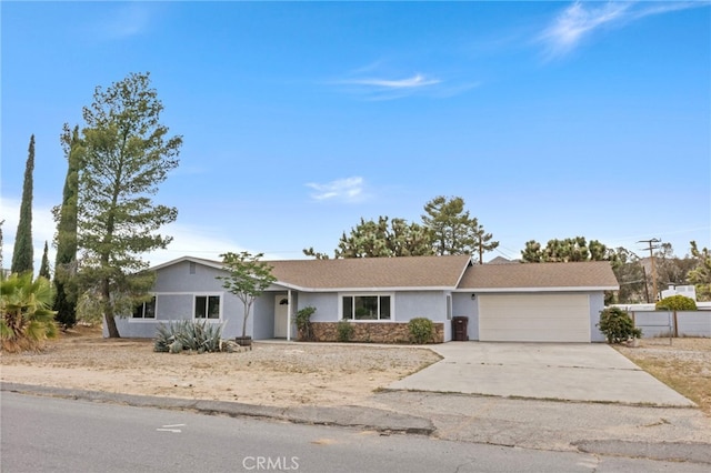 7010 Airway Ave, Yucca Valley, CA 92284 - ranch-style home with stucco siding, an attached garage, driveway, and stone siding