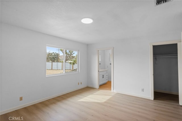 7010 Airway Ave, Yucca Valley, CA 92284 - unfurnished bedroom featuring light wood-style floors, a spacious closet, baseboards, and ensuite bathroom