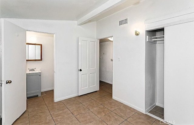 15521 Heartsease Ln, Victorville, CA 92395 - unfurnished bedroom with light tile patterned floors, washer / clothes dryer, a closet, baseboards, and beam ceiling