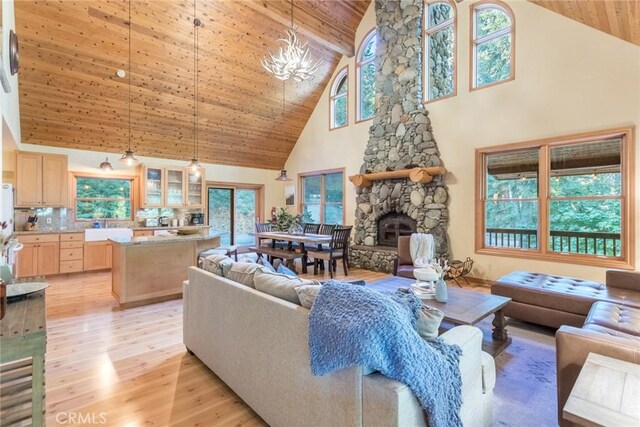 1900 Maple Dr, Weed, CA 96094 - living room with high vaulted ceiling, light wood-type flooring, wooden ceiling with exposed beams, a stone fireplace, and a chandelier