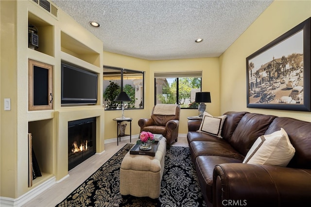76022 Honeysuckle Dr, Palm Desert, CA 92211 - living area with a textured ceiling, a glass covered fireplace, recessed lighting, and light wood-style floors