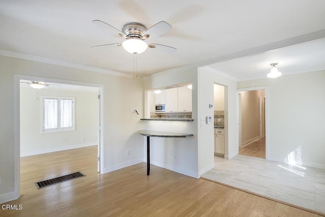3115 Evelyn St, La Crescenta, CA 91214 - kitchen featuring ceiling fan, stainless steel microwave, light wood finished floors, white cabinets, and ornamental molding