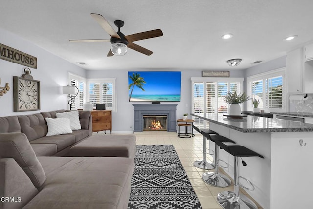 885 Oakland Hills Dr, Banning, CA 92220 - living area with light tile patterned flooring, a glass covered fireplace, ceiling fan, recessed lighting, and baseboards