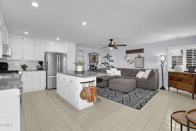 885 Oakland Hills Dr, Banning, CA 92220 - kitchen with freestanding refrigerator, a ceiling fan, open floor plan, decorative backsplash, and a kitchen island
