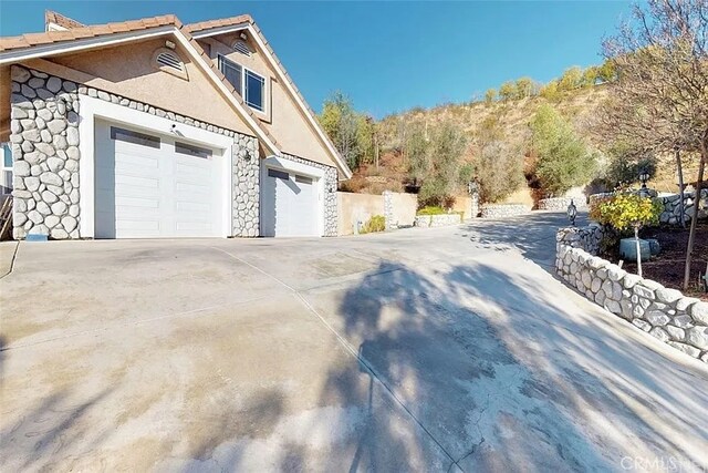 33710 Santiago Rd, Acton, CA 93510 - view of property exterior with stone siding, driveway, and a garage