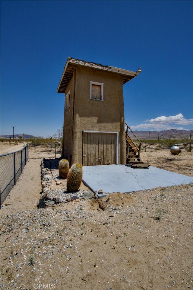 62853 Desert Trail Dr, Joshua Tree, CA 92252 - view of side of home featuring stairs, stucco siding, and a mountain view