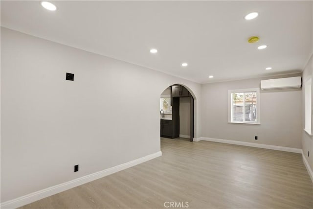 605 E Fredricks St, Barstow, CA 92311 - spare room featuring an AC wall unit, arched walkways, recessed lighting, light wood-type flooring, and baseboards