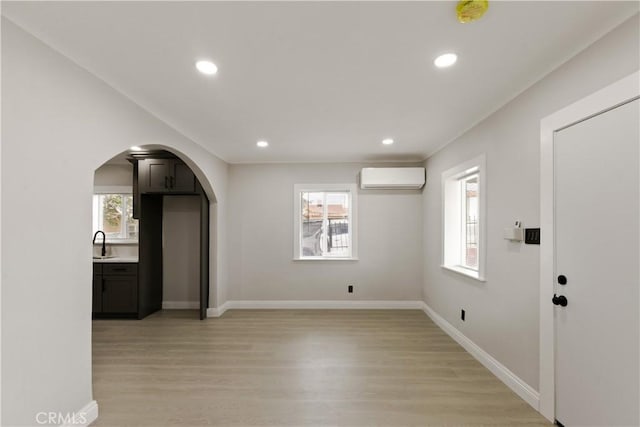 605 E Fredricks St, Barstow, CA 92311 - unfurnished living room featuring a wall mounted air conditioner, light wood finished floors, arched walkways, a sink, and recessed lighting