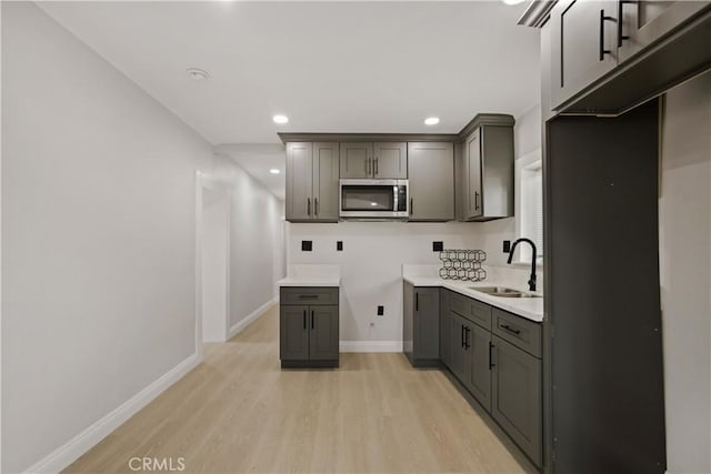 605 E Fredricks St, Barstow, CA 92311 - kitchen featuring a sink, stainless steel microwave, light wood-style floors, gray cabinetry, and recessed lighting