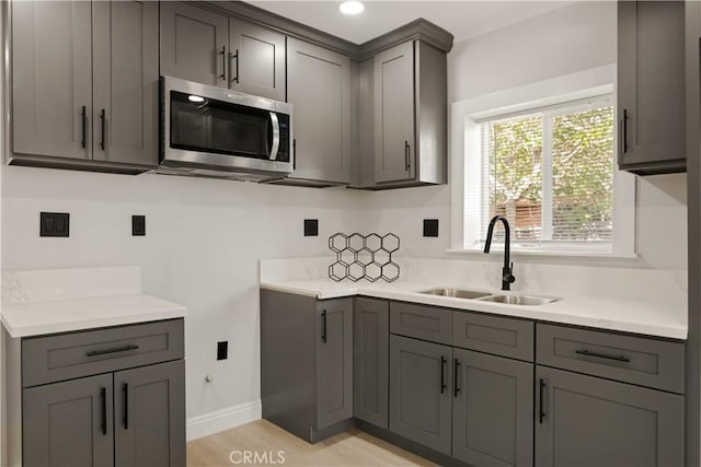 605 E Fredricks St, Barstow, CA 92311 - kitchen featuring stainless steel microwave, gray cabinetry, a sink, baseboards, and light countertops
