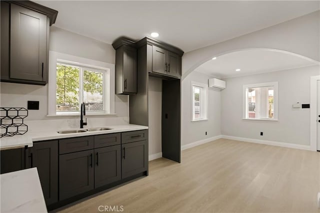 605 E Fredricks St, Barstow, CA 92311 - kitchen with a sink, an AC wall unit, light wood-style flooring, arched walkways, and recessed lighting