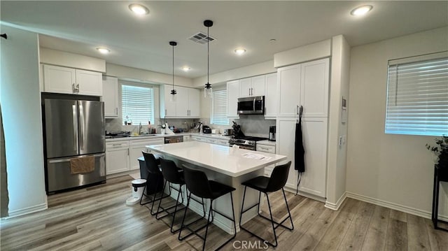 1416 Vigilant, Carson, CA 90746 - kitchen featuring appliances with stainless steel finishes, a breakfast bar area, white cabinetry, light countertops, and light wood-type flooring