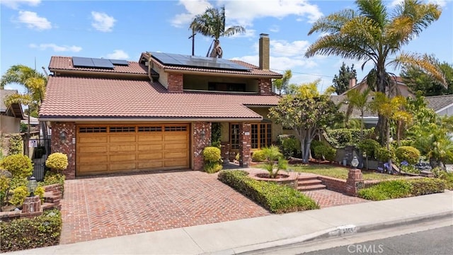 5144 Meadow Wood Ave, Lakewood, CA 90712 - view of front of house featuring a tile roof, a garage, decorative driveway, roof mounted solar panels, and brick siding