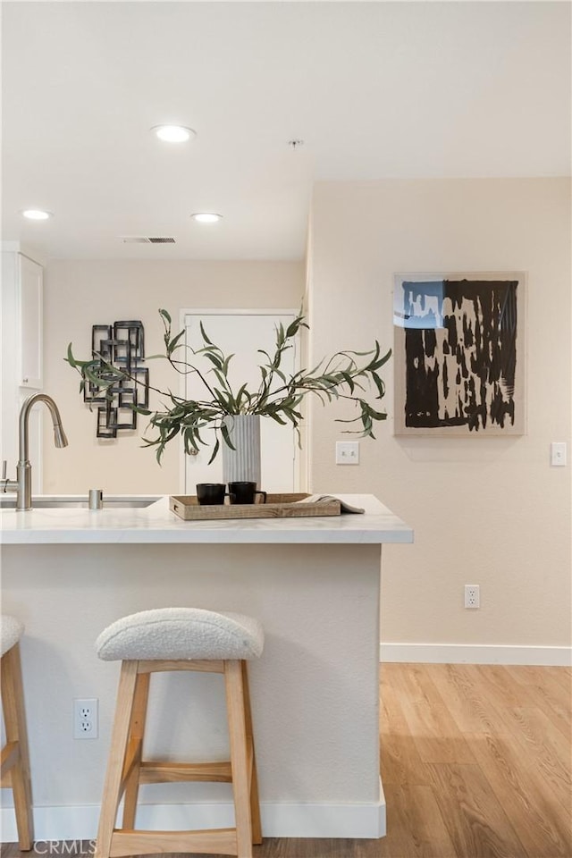 6375 Woodrow Ct Unit 3, Chino Hills, CA 91709 - kitchen with light wood-style floors, a kitchen bar, white cabinets, light countertops, and recessed lighting