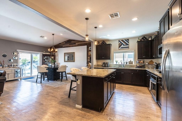 24802 Sandy Trail Pl, Menifee, CA 92584 - kitchen with stainless steel appliances, lofted ceiling, light stone counters, a chandelier, and light wood-style floors