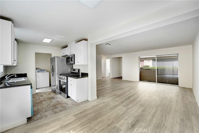 20235 Cohasset St Unit 6, Winnetka, CA 91306 - kitchen featuring appliances with stainless steel finishes, washer / clothes dryer, a sink, dark countertops, and white cabinets