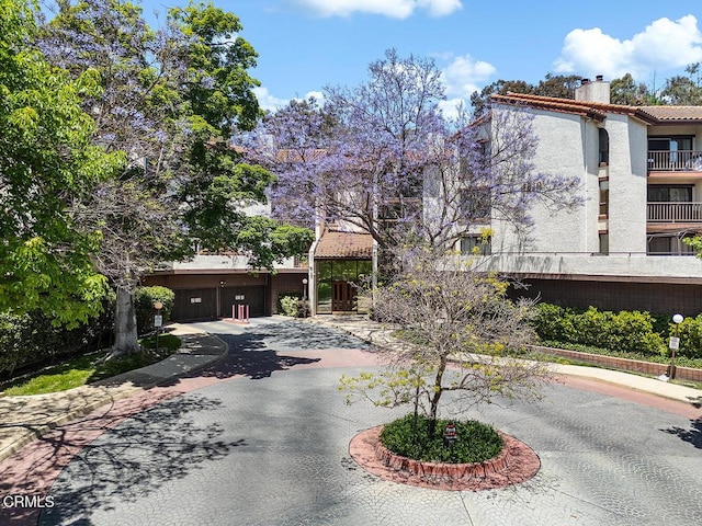 4210 Via Arbolada Unit 308, Los Angeles, CA 90042 - view of front facade featuring curved driveway, a chimney, stucco siding, and a garage
