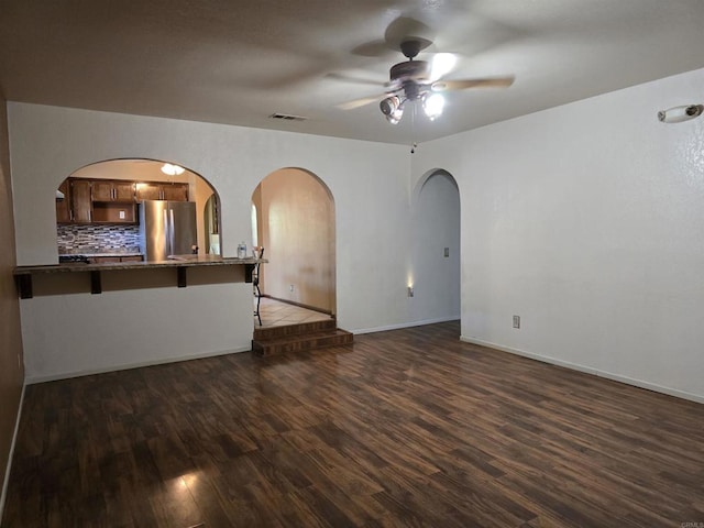 704 S H St, Imperial, CA 92251 - unfurnished living room featuring ceiling fan, dark wood finished floors, arched walkways, and baseboards