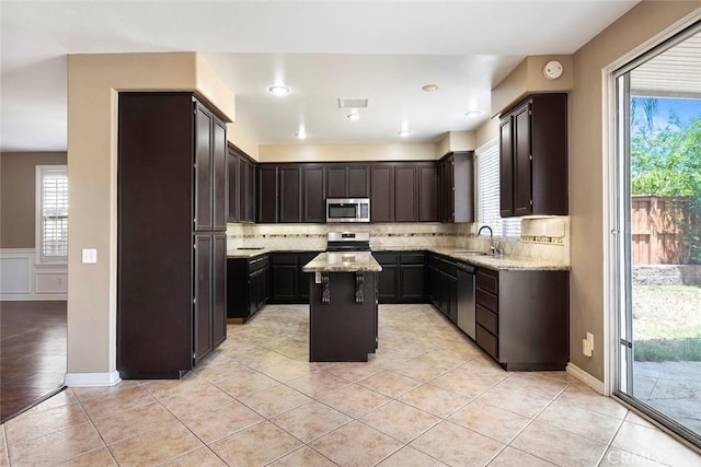 39766 Pinedale Way, Murrieta, CA 92562 - kitchen with appliances with stainless steel finishes, a center island, backsplash, light stone counters, and healthy amount of natural light