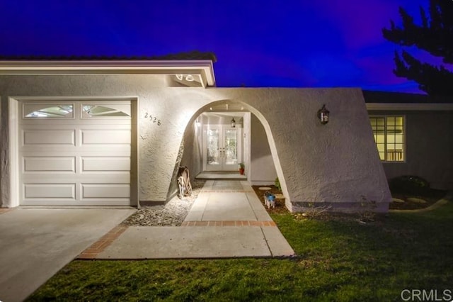 2528 Windmill View Rd, El Cajon, CA 92020 - exterior entry at night with a garage, stucco siding, french doors, and driveway
