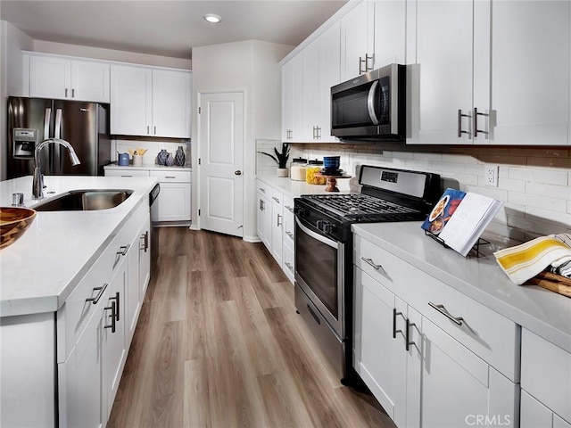 35390 Garcia St, Beaumont, CA 92223 - kitchen with appliances with stainless steel finishes, a sink, light countertops, wood finished floors, and white cabinets