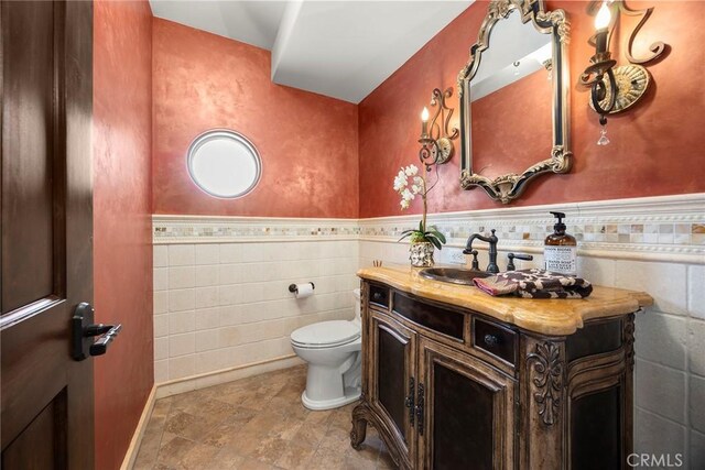 21925 Heatheridge Dr, Yorba Linda, CA 92887 - bathroom with tile walls, vanity, toilet, stone finish flooring, and a wainscoted wall
