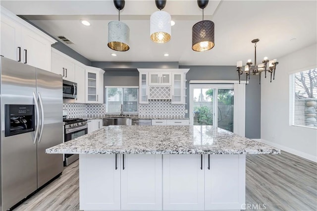5612 Sprague Ave, Cypress, CA 90630 - kitchen with appliances with stainless steel finishes, decorative backsplash, white cabinets, light wood-type flooring, and a center island