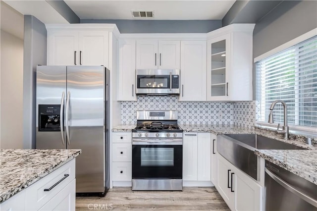 5612 Sprague Ave, Cypress, CA 90630 - kitchen featuring stainless steel appliances, a sink, white cabinetry, light stone countertops, and glass insert cabinets