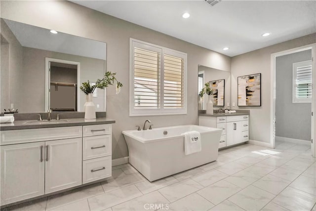 370 Sawbuck, Irvine, CA 92618 - bathroom with two vanities, marble look tile flooring, baseboards, a freestanding bath, and recessed lighting