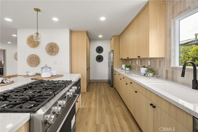 5161 E 27th St, Long Beach, CA 90815 - kitchen with appliances with stainless steel finishes, light wood-style flooring, light brown cabinets, decorative light fixtures, and decorative backsplash
